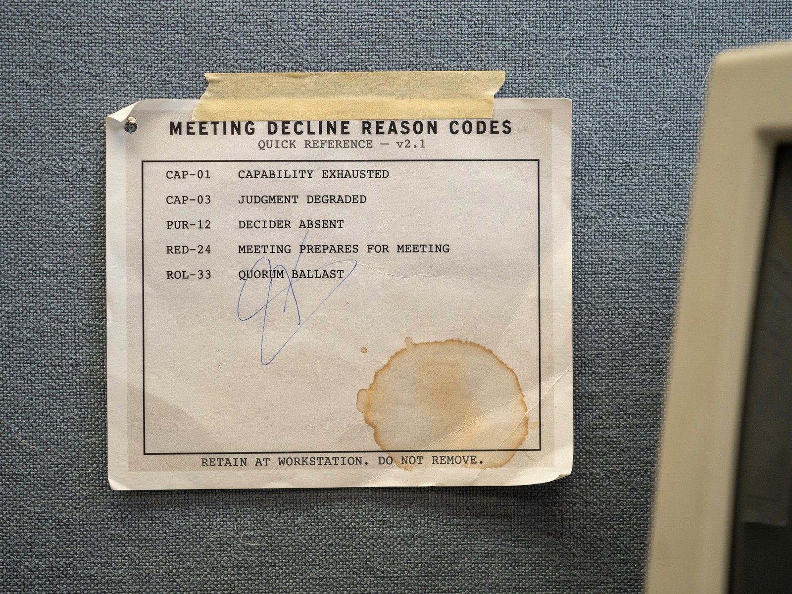 Photograph of a creased quick-reference card taped to a cubicle wall, listing five decline codes in typewriter text